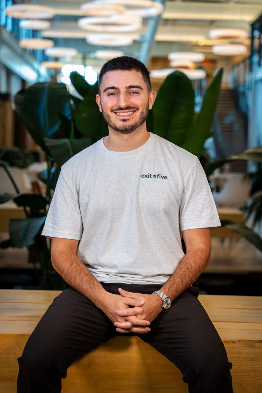 A guest in an Exit Five shirt smiling for a seated event portrait