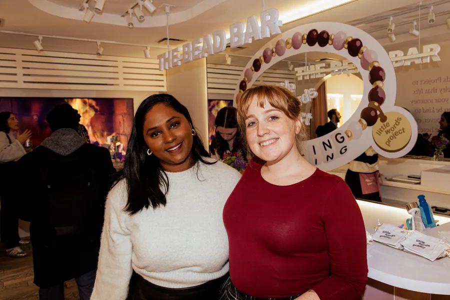 Two guests smiling in front of a Rippling activation