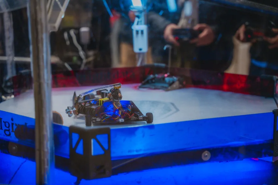 A robot combat arena under blue event lighting