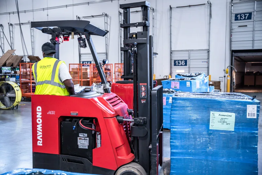 A Barrett Distribution operator moving a pallet with a red forklift