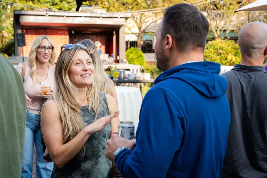 Guests smiling during a conversation at the outdoor Drive 2025 reception