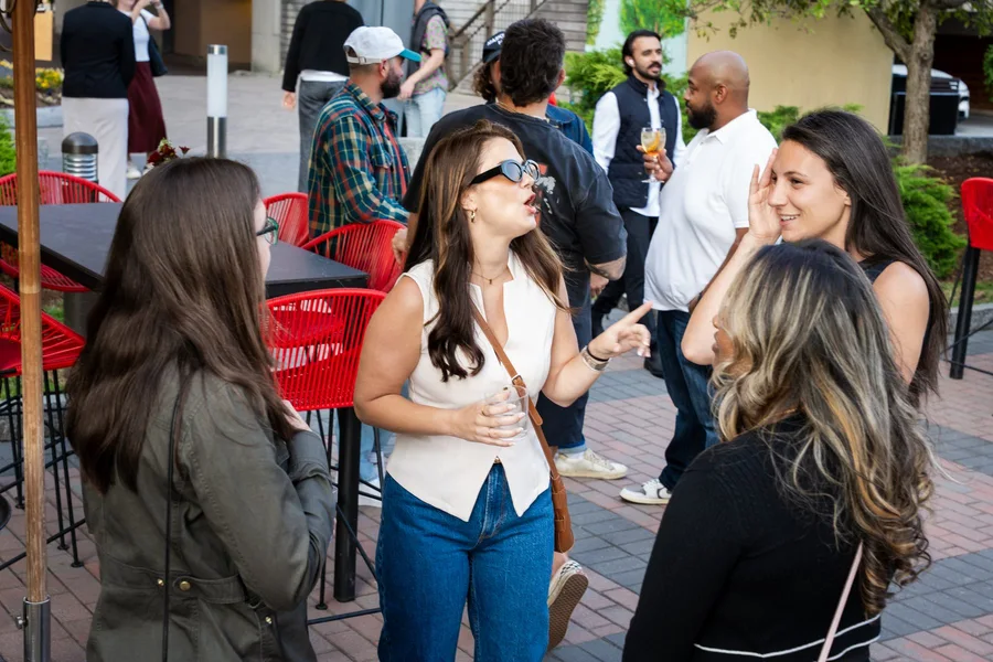 Three guests smiling and talking at an outdoor reception