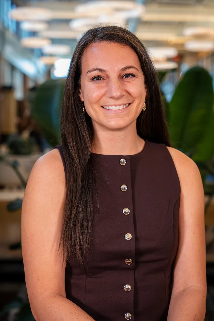 A guest in a burgundy top smiling for an event headshot