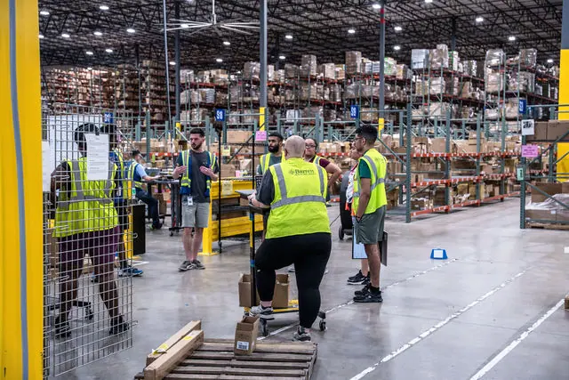 Barrett employees operating warehouse automation behind a safety fence