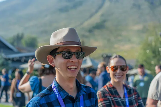 A smiling Highline attendee trying on a hat outdoors