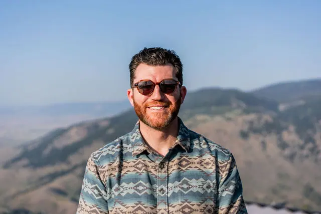 A bearded Highline attendee posing with the mountains behind him