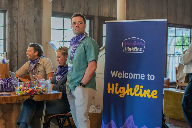 An attendee beside the branded Highline welcome sign