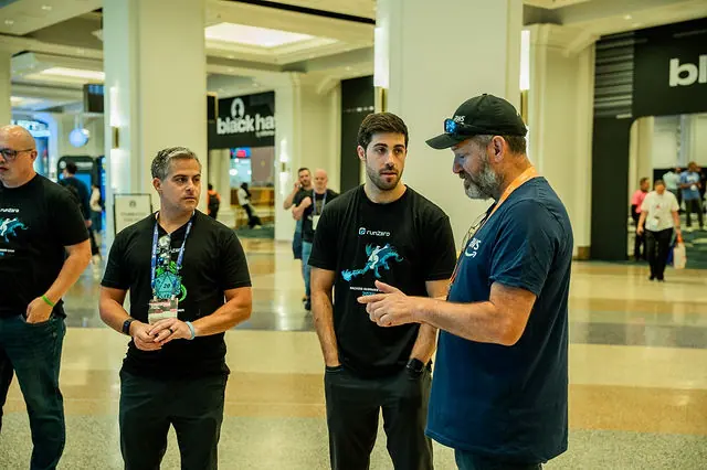 Three attendees talking at the runZero Black Hat activation