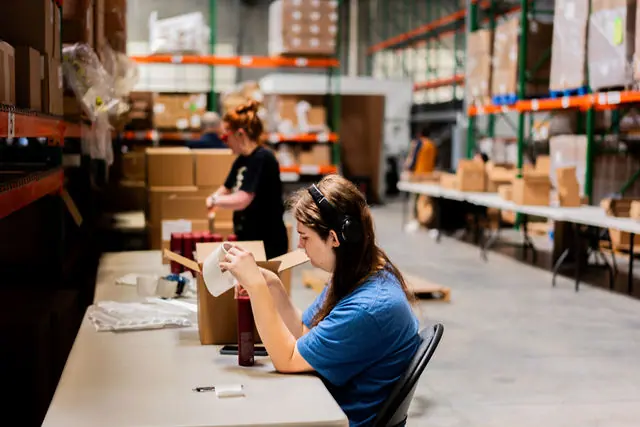 A Revamp Fulfillment employee handling an order at a packing station